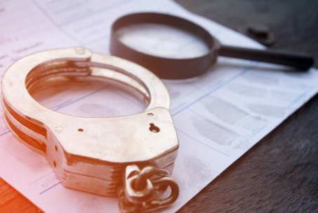 handcuffs and magnifying glass on top of fingerprints - still life photo